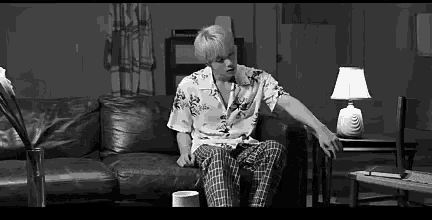 a man is sitting on a couch in a living room with a lamp .