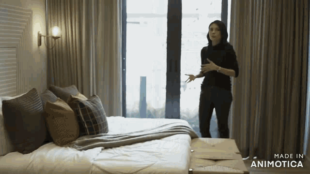 a woman stands in front of a bed with the words made in animotica on the bottom right
