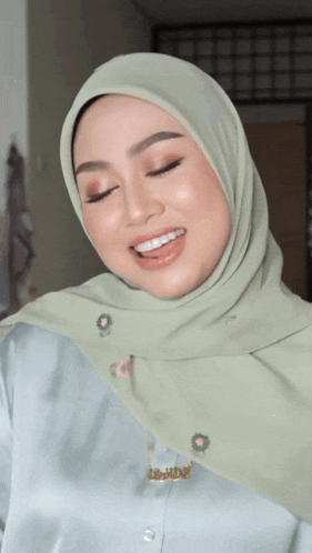 a woman wearing a green hijab and a necklace that says i love you