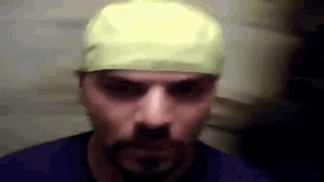 a man wearing a yellow hat and a blue shirt is making a funny face .