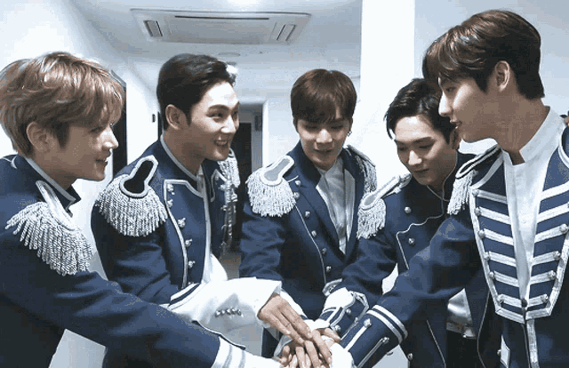 a group of young men in blue military uniforms are putting their hands together in a huddle