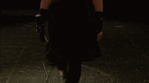 a person in a black coat is walking in the dark