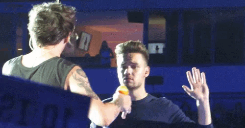 two men are standing next to each other on a stage and one of them is feeding the other something .