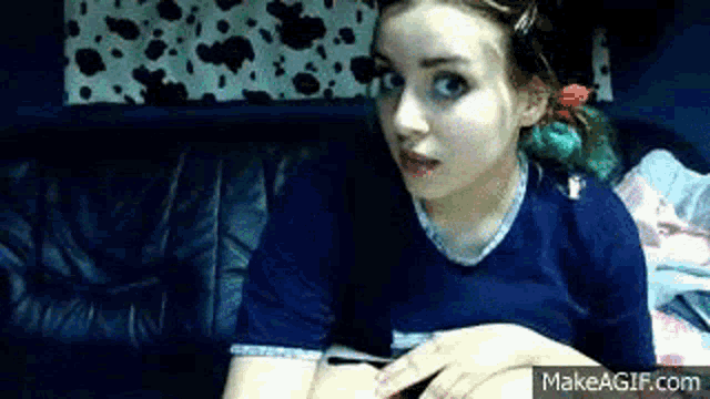 a girl in a blue shirt is sitting on a leather couch .