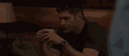 a man is sitting at a table with a cup of coffee in his hand and a watch on his wrist .