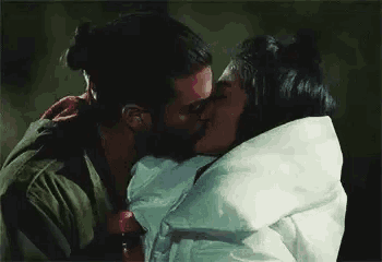 a man and a woman are kissing each other while wrapped in a blanket .