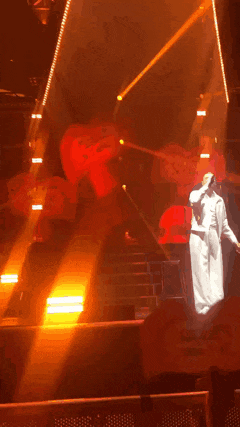 a man in a white robe is standing on a stage with a microphone