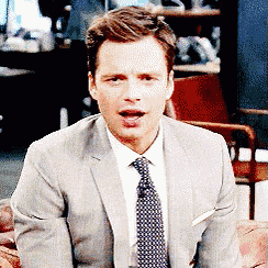 a man in a suit and tie is sitting on a chair with his mouth open