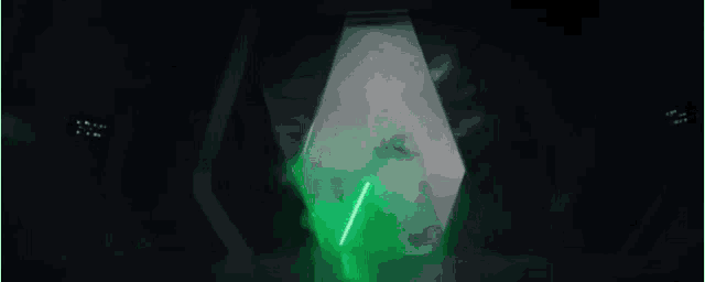 a person holding a green lightsaber in a dark room .