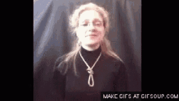 a woman wearing a black shirt and a necklace with a rope around her neck .