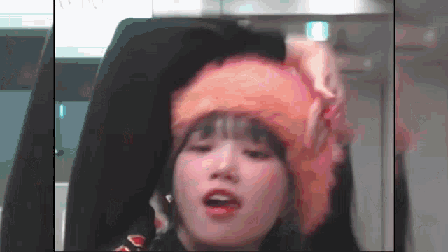 a woman wearing an orange hat is making a funny face while sitting in a car .