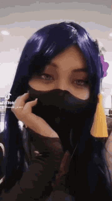 a woman wearing a purple wig and a black mask .