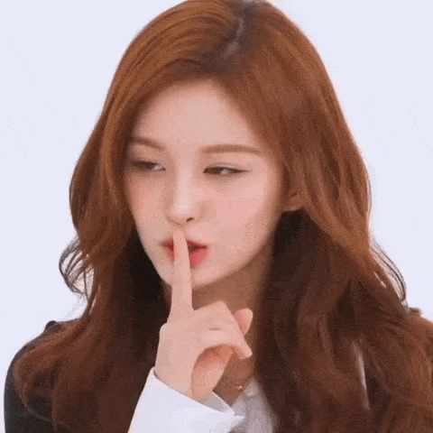 a woman with long red hair is making a shhh gesture with her finger to her lips .