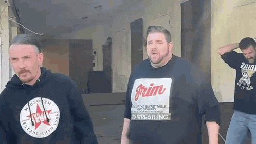 three men are standing next to each other and one of them is wearing a shirt that says grim