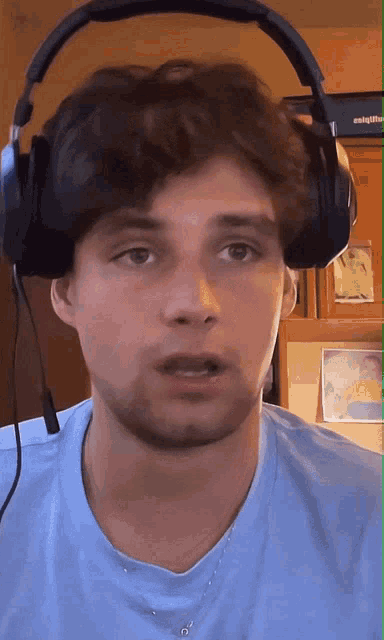 a man wearing headphones and a blue shirt looks at the camera