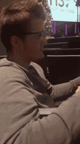 a man wearing glasses is sitting in front of a screen that says east high school