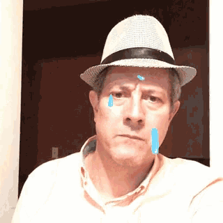 a man wearing a hat is crying with a blue tear on his forehead