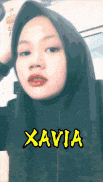 a woman wearing a hijab has the name xavia written on her face
