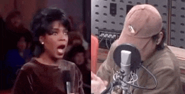 a woman is screaming into a microphone next to a man in a hat .