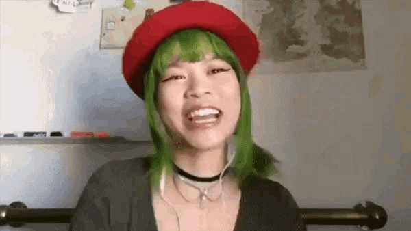 a woman with green hair wearing a red hat and headphones .