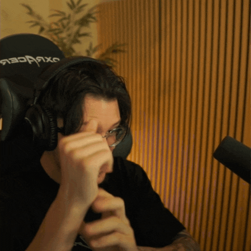 a man wearing headphones and glasses is sitting in front of a microphone with a chair that says oxforces on it