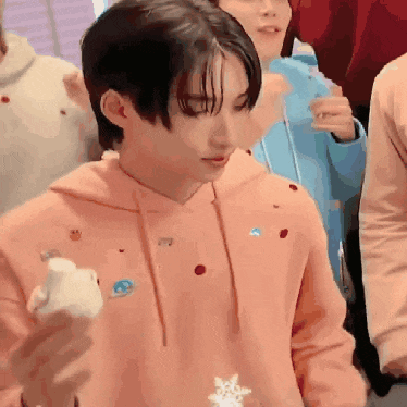 a young man in a pink hoodie is holding a marshmallow .