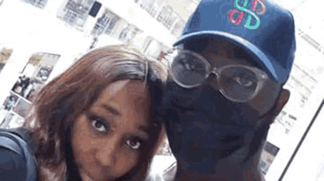 a man and a woman are posing for a picture . the man is wearing a mask and glasses .