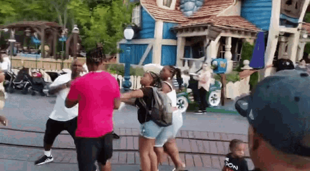 a group of people are dancing in front of a blue building .