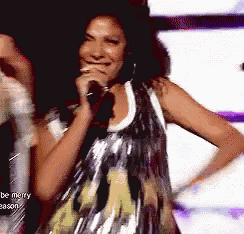a woman singing into a microphone with the words be merry season on the bottom right