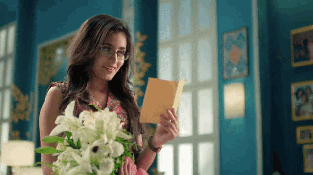 a woman holding a bouquet of flowers and reading a letter