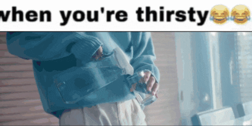 a person in a blue sweater pouring water into a glass