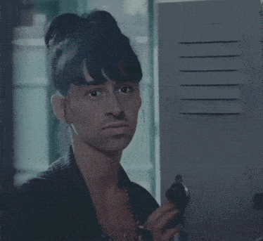 a man with a bun on his head is standing in front of a locker