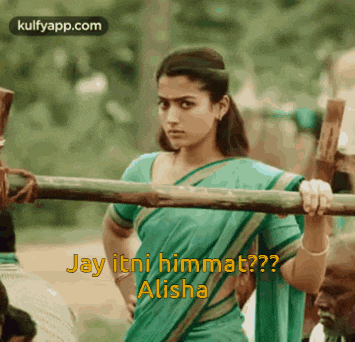 a woman in a green saree is holding a wooden pole and says jay itni himmat alisha