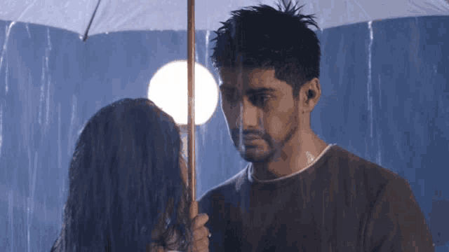 a man is holding an umbrella over a woman 's head in the rain
