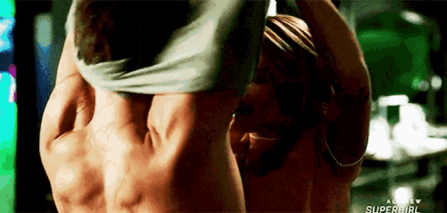 a man and a woman are standing next to each other and the woman is taking off her shirt .