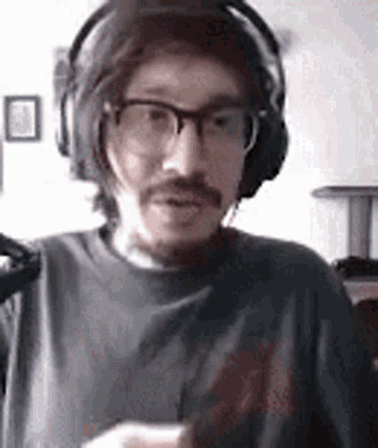 a man wearing glasses and headphones is sitting in a room .