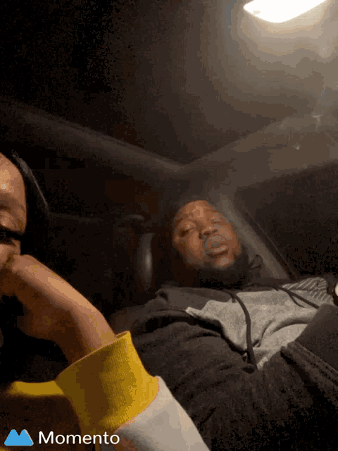 a man and a woman are sitting in a car with the word momento on the bottom