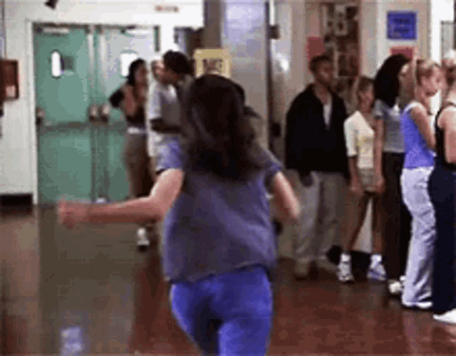 a group of people are standing in a hallway with a yellow sign that says no