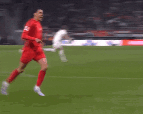 a soccer player wearing a red jersey with the number 13 on it is running on the field