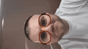 a man wearing glasses and a white shirt is smiling