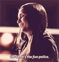 a woman with long hair is smiling and saying `` uh oh , it 's the fun police '' .