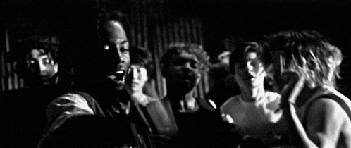 a black and white photo of a group of people standing next to each other in a dark room .