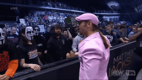 a man in a pink suit stands in front of a wall that says matthew jackson on it