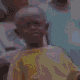 a young boy wearing a yellow shirt is standing in front of a crowd .