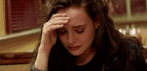 a woman is crying while holding her head with her hand .