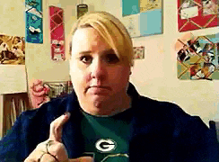 a woman wearing a green bay packers shirt is making a face
