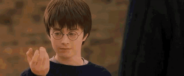 harry potter is holding a golden snitch in his right hand