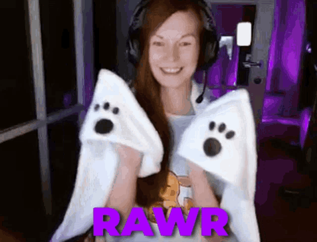a woman wearing headphones is holding two white paw shaped pillows with the word rawr in purple