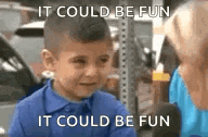 a little boy in a blue shirt is talking to a woman in a parking lot .