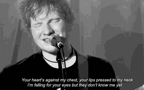 a man singing into a microphone with the words " your heart 's against my chest "